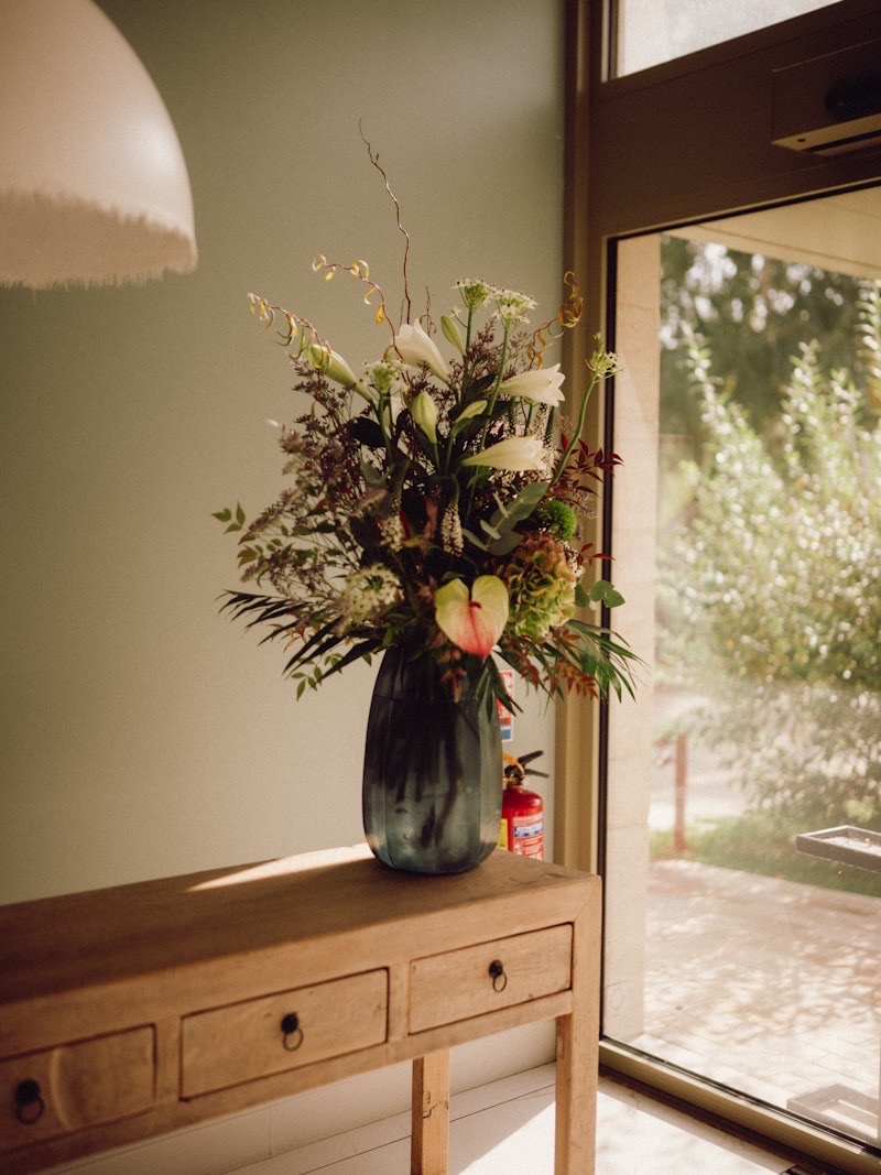 Sunlit console table with a vase of olive branches beside a framed print in a calm Coral Gables office
